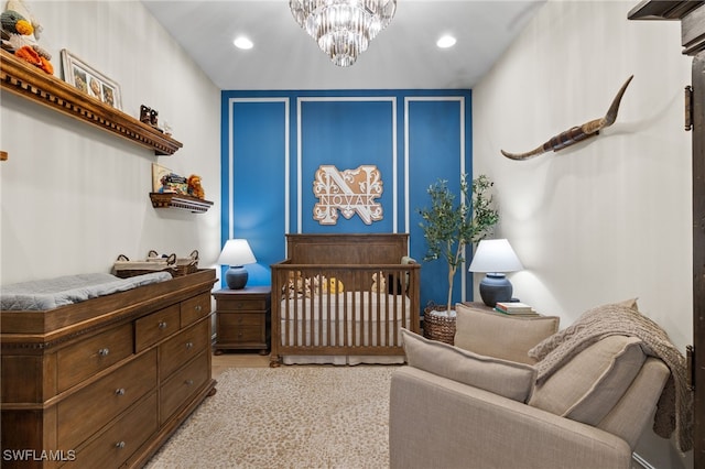 carpeted bedroom featuring a crib and a notable chandelier