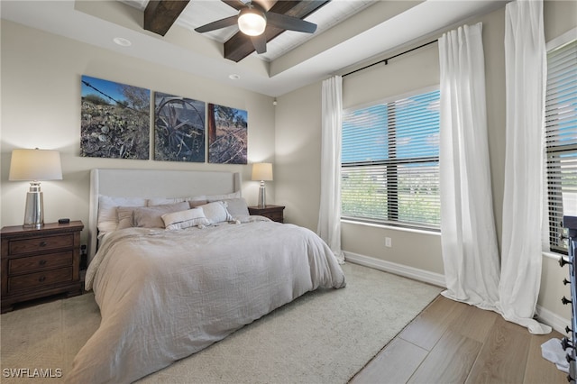 bedroom with beam ceiling, light hardwood / wood-style floors, and ceiling fan