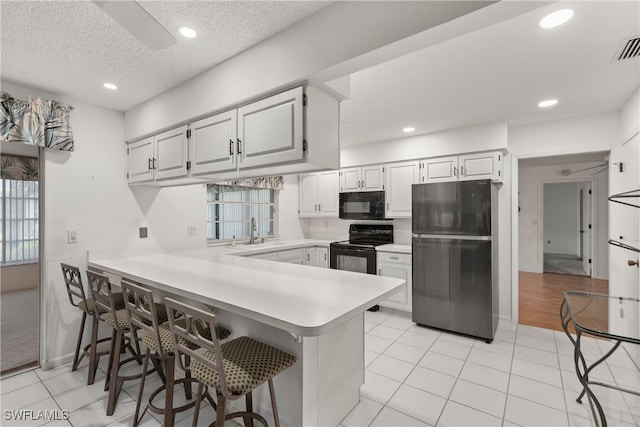 7076 E Brandywine Cir, Fort Myers, FL 33919 - kitchen with black appliances, light countertops, a peninsula, light tile patterned floors, and a sink