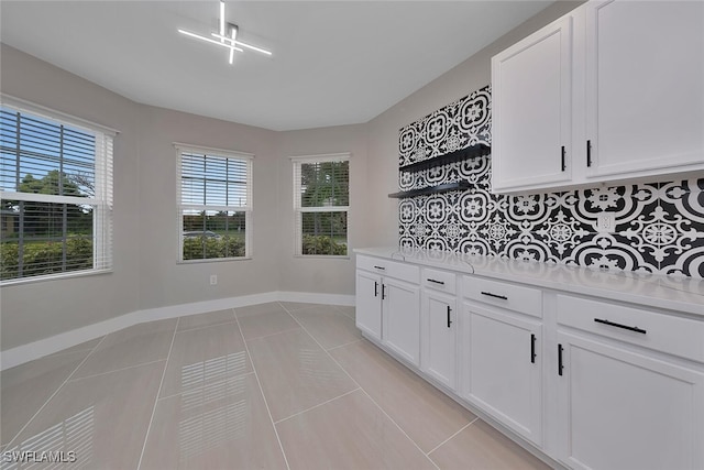 kitchen with decorative backsplash, white cabinetry, and light tile patterned floors