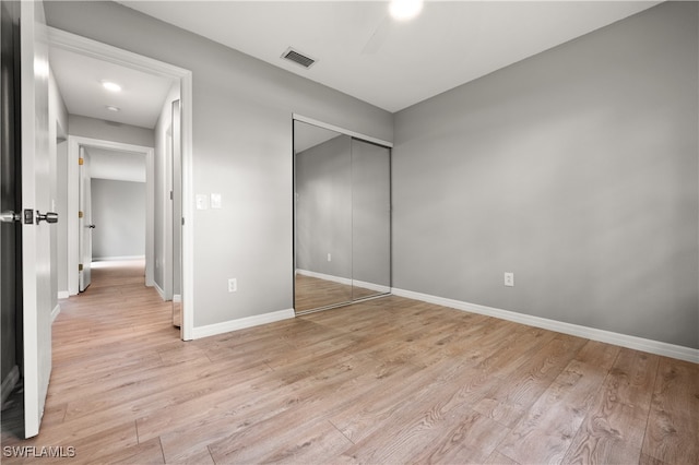 unfurnished bedroom featuring light wood-type flooring and a closet