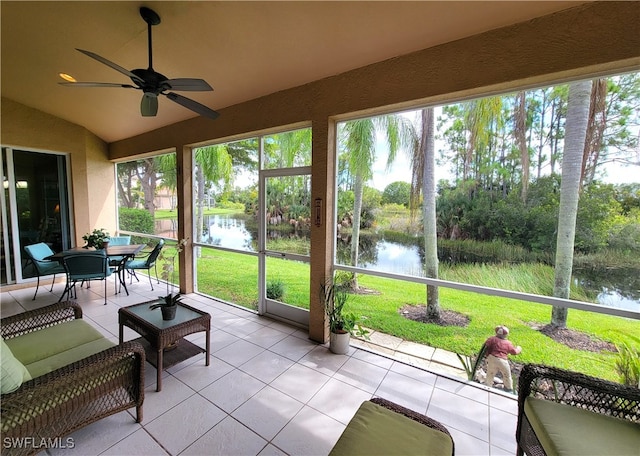 sunroom / solarium with ceiling fan, a water view, and lofted ceiling