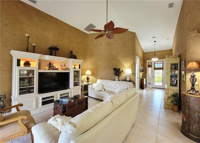 tiled living area with visible vents, ceiling fan, and a high ceiling