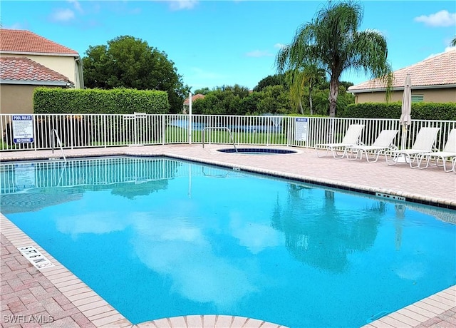 pool featuring fence, a community hot tub, and a patio