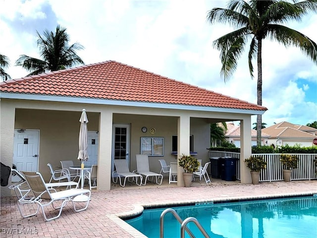 rear view of house featuring a patio area, fence, a fenced in pool, and stucco siding