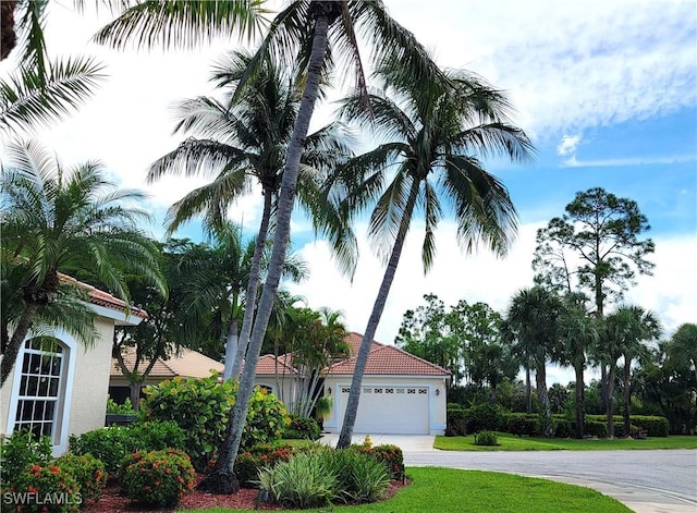 view of front of house featuring a tile roof, stucco siding, concrete driveway, an attached garage, and a front lawn