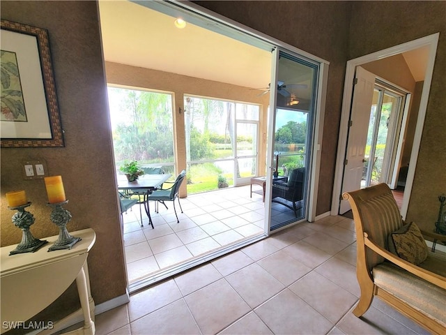 entryway with light tile patterned floors, a ceiling fan, baseboards, and a sunroom