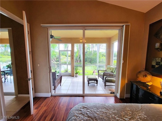 bedroom with access to outside, baseboards, vaulted ceiling, and wood finished floors