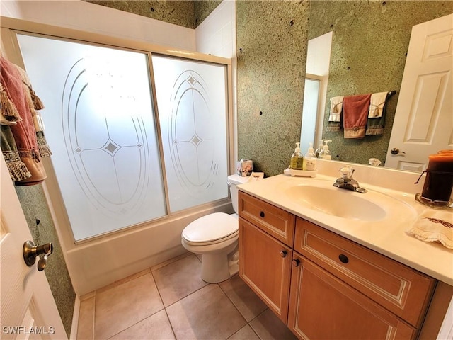 bathroom featuring tile patterned flooring, enclosed tub / shower combo, vanity, and toilet