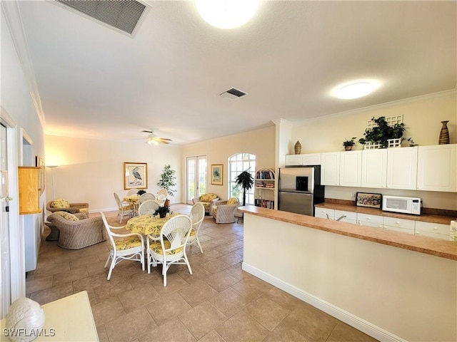 kitchen featuring white microwave, visible vents, stainless steel refrigerator with ice dispenser, and open floor plan