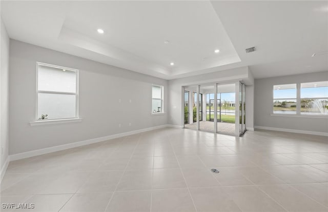 unfurnished room featuring a tray ceiling and light tile patterned floors