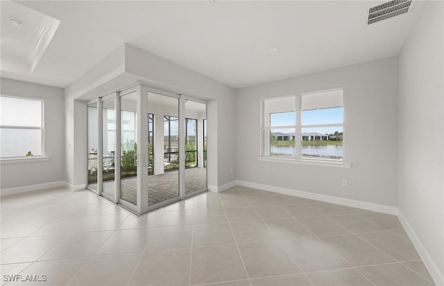 spare room featuring light tile patterned floors and a water view