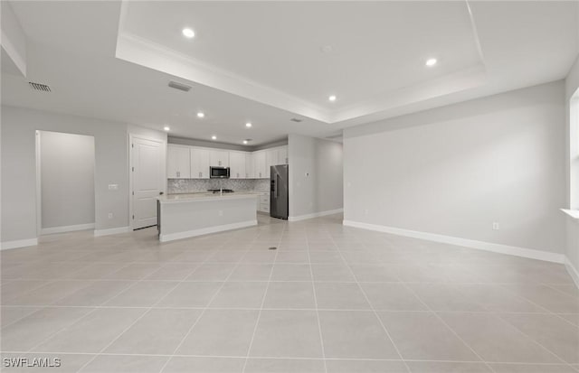 unfurnished living room featuring a raised ceiling and light tile patterned floors