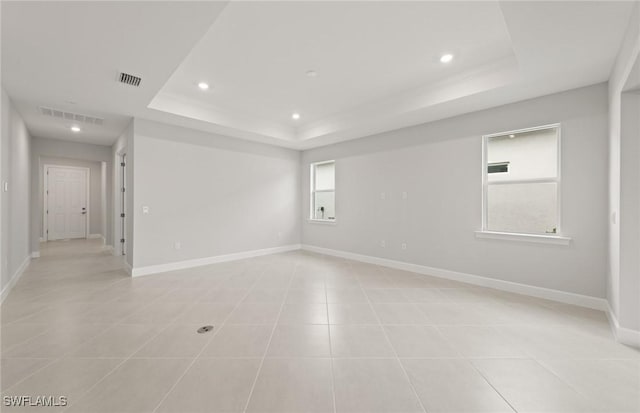 tiled spare room featuring a raised ceiling