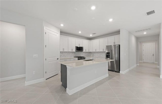 kitchen with tasteful backsplash, white cabinetry, an island with sink, sink, and stainless steel appliances