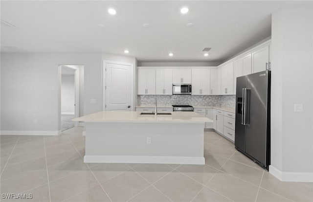 kitchen featuring sink, white cabinets, backsplash, a kitchen island with sink, and stainless steel appliances