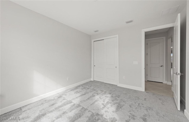 unfurnished bedroom featuring a closet and light carpet