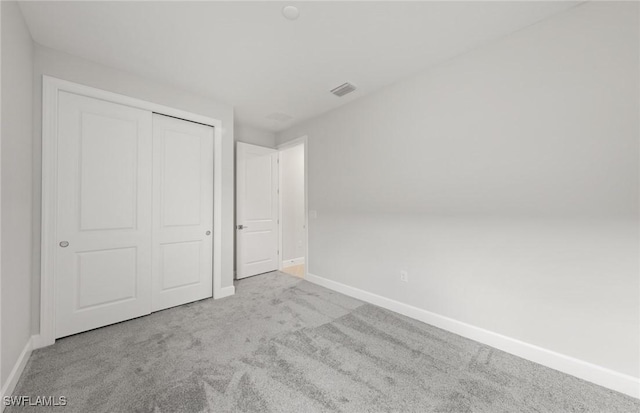 unfurnished bedroom with light carpet and a closet