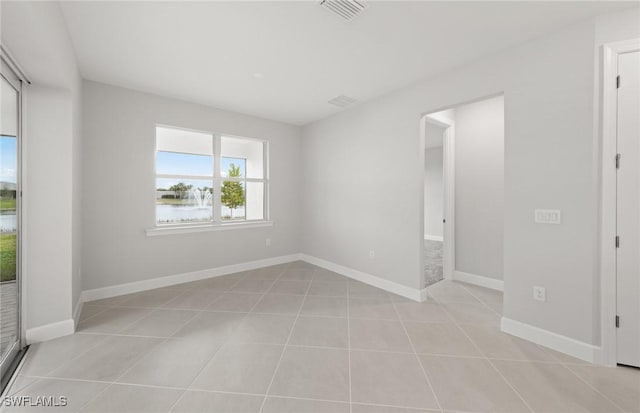 tiled spare room featuring a water view