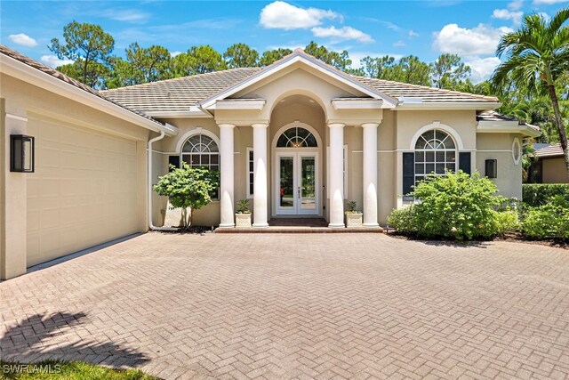 view of exterior entry featuring a garage and french doors