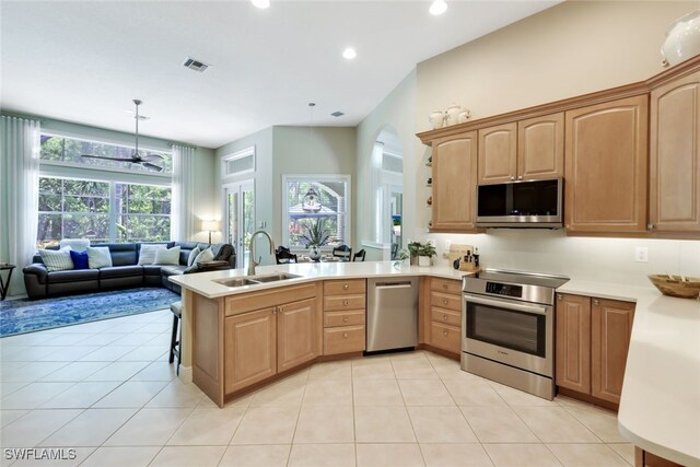 kitchen featuring pendant lighting, appliances with stainless steel finishes, light tile patterned floors, sink, and kitchen peninsula