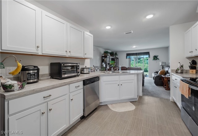 kitchen with sink, light carpet, white cabinetry, stainless steel appliances, and kitchen peninsula