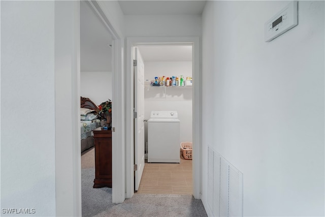 hallway with light carpet and washer / dryer