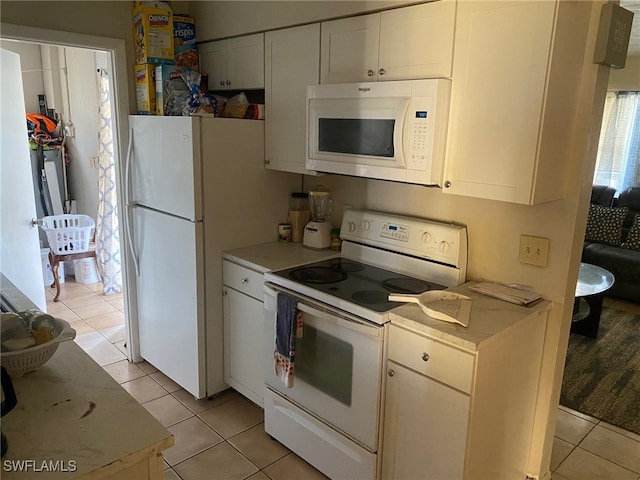 kitchen with white appliances, white cabinetry, and light tile patterned floors