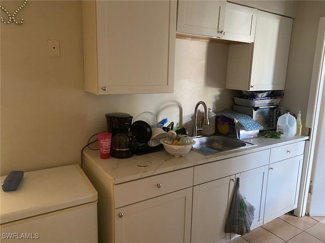 kitchen with sink, light tile patterned floors, and white cabinets