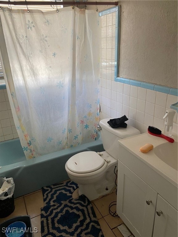 full bathroom with tile walls, vanity, toilet, tile patterned flooring, and shower / tub combo with curtain