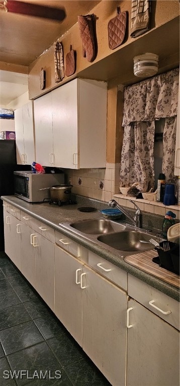 kitchen featuring dark tile patterned flooring, white cabinetry, sink, and tasteful backsplash