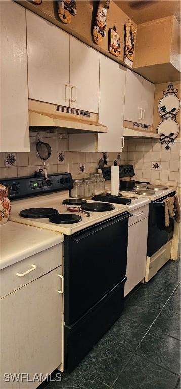 kitchen featuring white stove, backsplash, dark tile patterned flooring, white electric range, and white cabinets