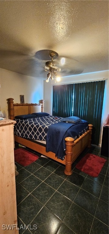 bedroom featuring dark tile patterned flooring, ceiling fan, and a textured ceiling