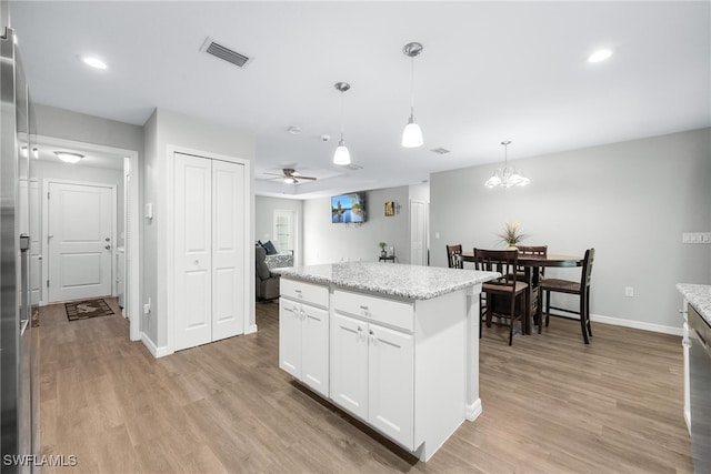 kitchen with a center island, white cabinets, ceiling fan, decorative light fixtures, and light hardwood / wood-style floors