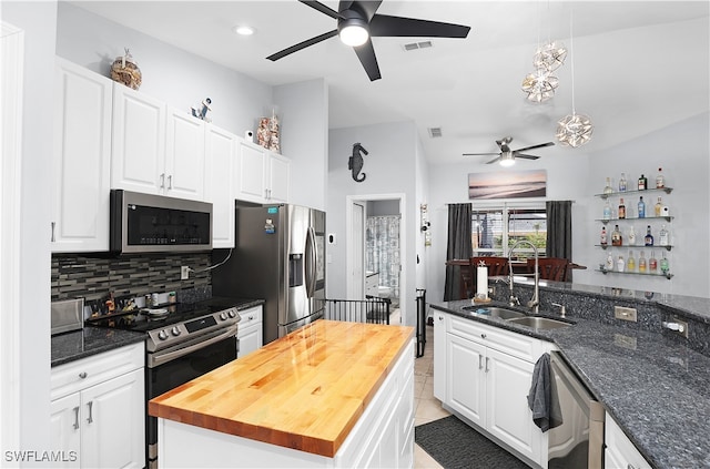 kitchen featuring sink, appliances with stainless steel finishes, a kitchen island, white cabinets, and wood counters