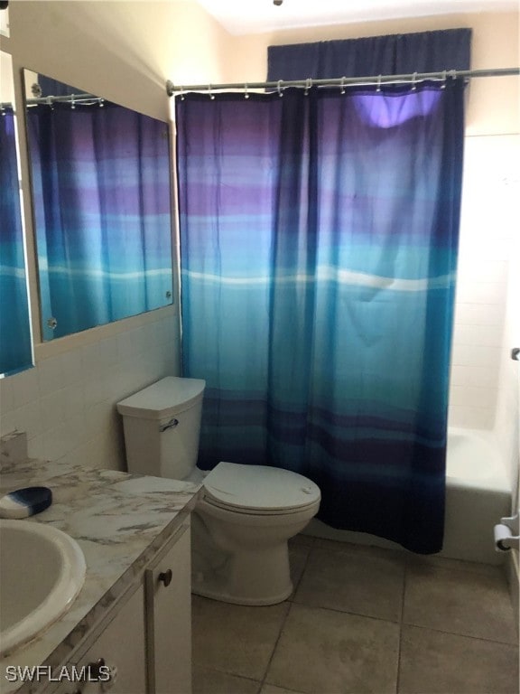 full bathroom with tile walls, tile patterned flooring, shower / bath combo with shower curtain, vanity, and toilet