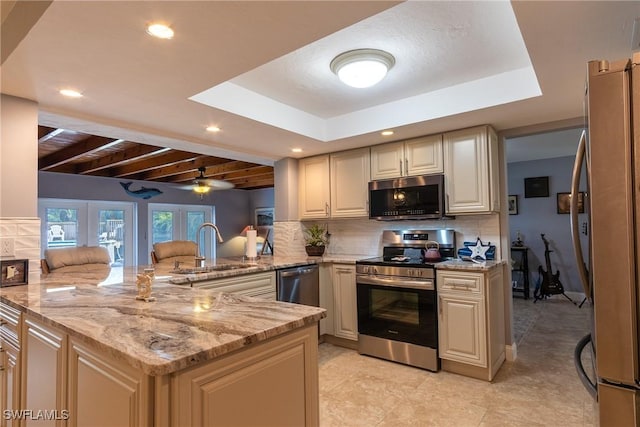 kitchen featuring kitchen peninsula, sink, light stone counters, ceiling fan, and stainless steel appliances