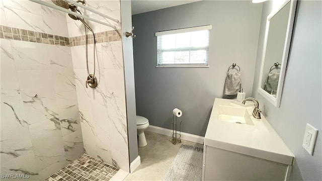 bathroom with tiled shower, vanity, and toilet