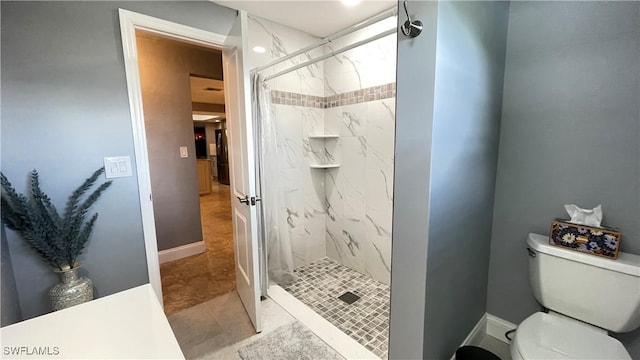 bathroom featuring tiled shower and toilet