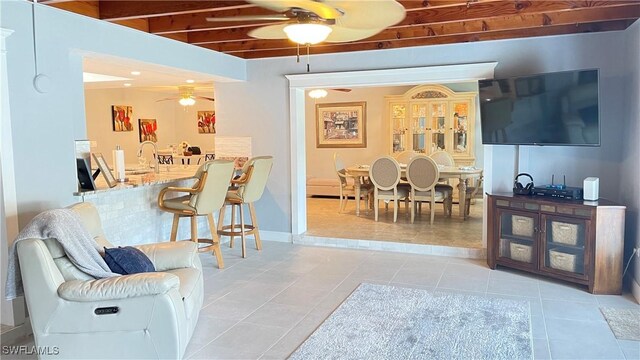 living room with light tile patterned flooring, sink, and beam ceiling