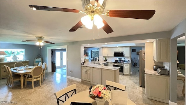 kitchen featuring appliances with stainless steel finishes, a wealth of natural light, light stone counters, and kitchen peninsula