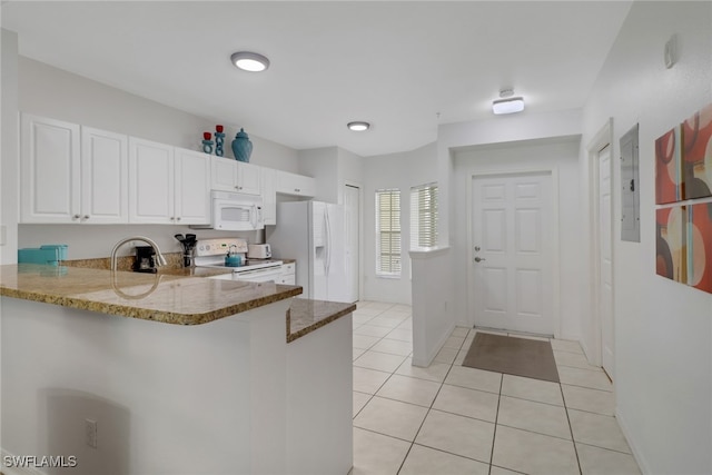 kitchen featuring light tile patterned floors, a peninsula, white appliances, white cabinets, and dark stone countertops