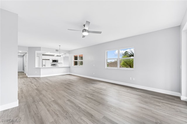 unfurnished living room with ceiling fan with notable chandelier and light wood-type flooring