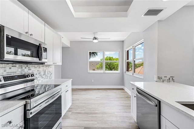 kitchen featuring white cabinetry, stainless steel appliances, tasteful backsplash, and light wood-type flooring