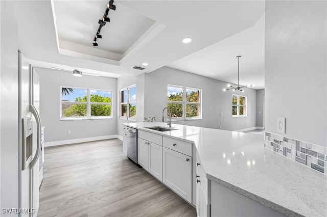 kitchen featuring a raised ceiling, an inviting chandelier, white cabinetry, stainless steel appliances, and sink