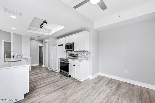 kitchen with appliances with stainless steel finishes, sink, a raised ceiling, white cabinetry, and light hardwood / wood-style flooring