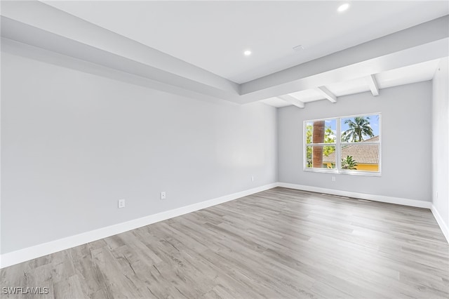 unfurnished room with beamed ceiling and light hardwood / wood-style flooring