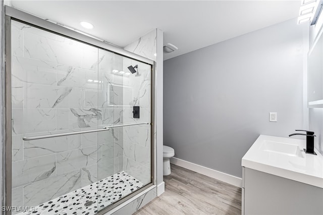 bathroom featuring toilet, a shower with shower door, hardwood / wood-style flooring, and vanity