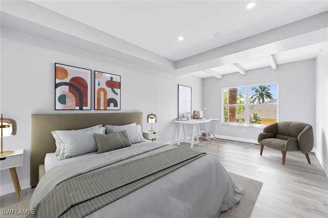 bedroom with beamed ceiling and light hardwood / wood-style floors