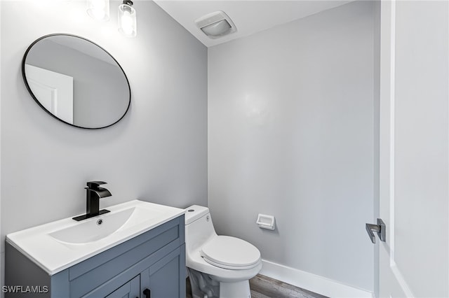 bathroom with toilet, vanity, and wood-type flooring